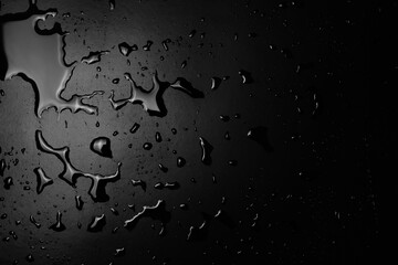 Water puddle and droplets isolated on black background and texture