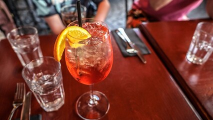 Elegant Sparkling Aperol Spritz cocktail with Vibrant Orange Slice on Dark Red Table Setting for Festive Occasion