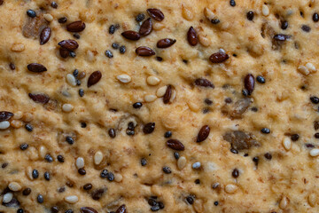 Background and texture of whole grain cookies made from flax, sesame and sunflower seeds, closeup, top view. Homemade healthy trendy cereal cookies with various seeds