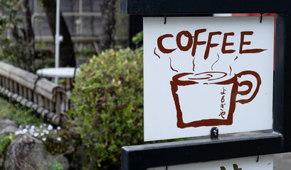 Coffee shop sign displaying steaming cup and japanese characters