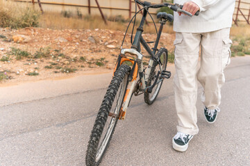 Young man pushing his bicycle Close-up on the road. Active lifestyle outdoors