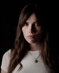 Studio portrait of a young Caucasian woman with long brown hair and silver necklace with star...
