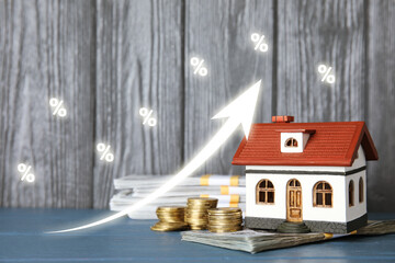 Increase in real estate value. House model and money on table. Growing price represented by arrow...