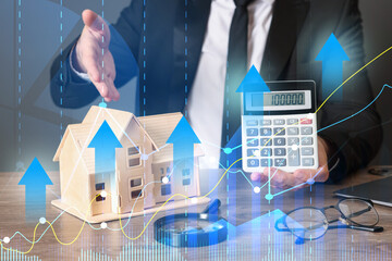 Increase in real estate value. Man pointing at house model and showing calculator, closeup. Graph...