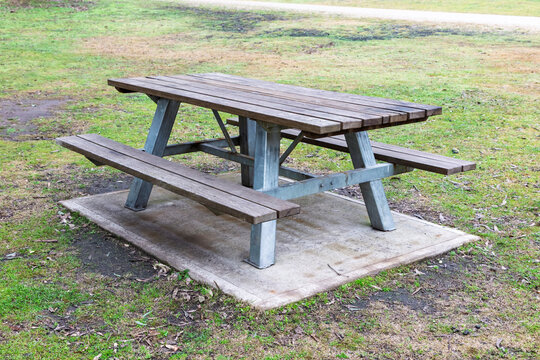 Photograph of a fixed in place reasonably well maintained family sized wood and steel picnic table with adequate seating located in a large public use campground facility.