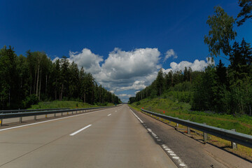 Naklejka premium Highway wide road, transport and blue sky with clouds on a summer day