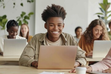 Happy young male student smiling and using laptop in classroom with diverse classmates