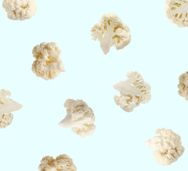 Fresh cauliflower florets falling on light blue background