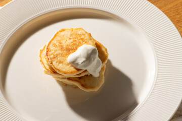 Small stack of fluffy pancakes topped with creamy goodness, resting on a white plate, creating a delightful and simple breakfast scene