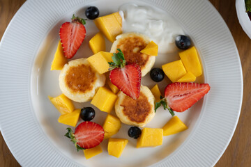 Delicious cheesecakes served with strawberries, blueberries, mango and yogurt, creating a colorful and healthy breakfast or dessert option