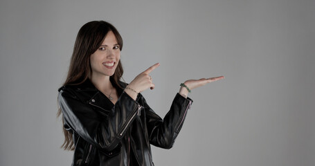 Smiling artist pointing with index finger and showing with open hand palm up on gray background