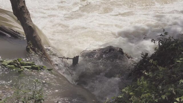 Texas 2025 flood water flowing over rock near river shoreline
