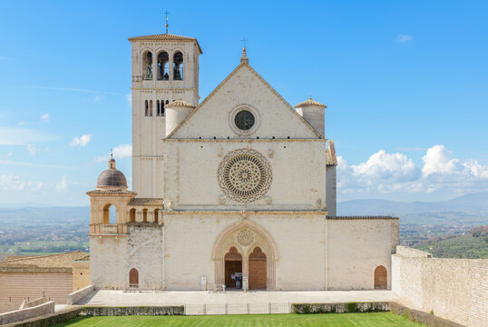 Facade of the Basilica of Saint Francis in Assisi, Italy, featuring a rose window, Gothic portal, and upper church elevation.