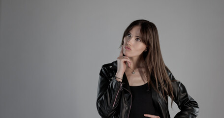 Portrait of a thoughtful young woman wearing black clothes and posing with hand on chin