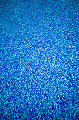 Obraz premium Bright blue mosaic tile texture under rippling pool water with sunlight reflections. Summer aquatic background with clear liquid surface.