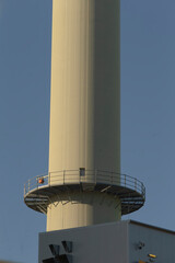 There is a very tall, white structure in the form of a tower that features a balcony situated on the top of it, providing a stunning view