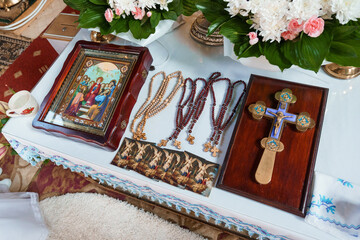 Orthodox Religious Ceremony Setup with Icon, Rosaries, Cross, and Floral Arrangements on Table with Lace