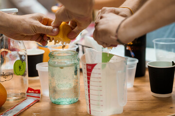 Hands Juicing Fresh Oranges into Glass Jars, Summer Drink Preparation, Bright Kitchen Setting, Citrus Fruits, Natural Food, Warm Light.