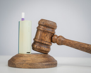 Judge's gavel and e-cigarette. Smoking ban. Tobacco heating systems. 