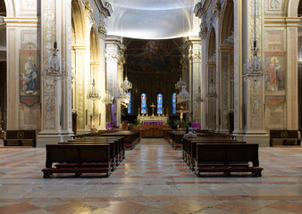 Baroque church interior with frescoed apse, chandeliers, pews, and stained glass windows in Ferrara...