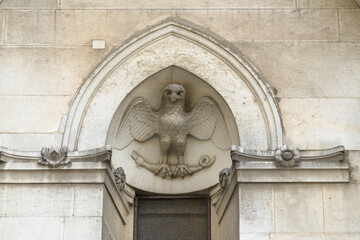 Stone relief of eagle grasping serpent above Gothic arch on facade of San Michele in Foro, Lucca,...