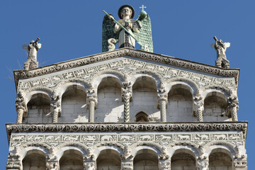 Facade of San Michele in Foro, Lucca, Italy, with arcades, decorative columns and marble sculpture...