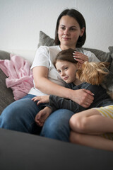 Mother hugging her now smiling daughter while sitting on the couch. Concept: family love, comfort, emotional support, joyful reunion, close bond.