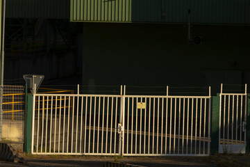 A white wooden fence adorned with a bright yellow warning sign positioned prominently on it,...
