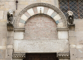 Detail of the Romanesque marble portal with sculpted lions and Latin inscription, Santa Maria...