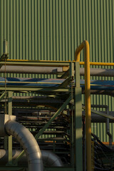 In front of a green building, there is a prominent yellow pipe that catches the eye. It adds a...