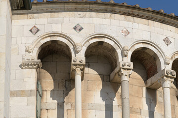 Romanesque arcade with sculpted capitals and heads on the apse of San Martino Cathedral, Lucca,...