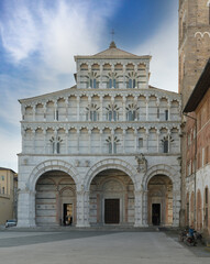 San Martino Cathedral and bell tower in Lucca, Italy, Romanesque facade with sculpted arches and...