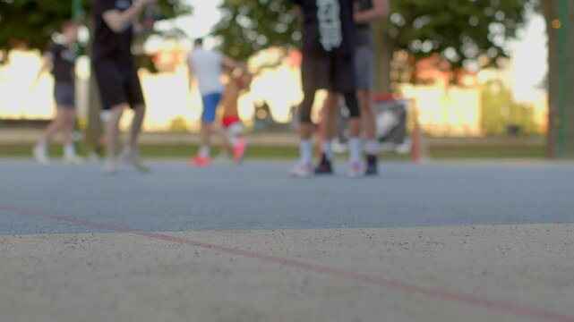 A group of people enthusiastically engaging in an exciting basketball game at an openair court, complete with visible court markings and a lively group of spectators in the background