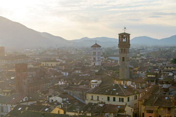 View from Torre Guinigi over rooftops of Lucca, Tuscany, Italy, showing Torre delle Ore and bell...