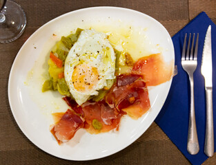 Appetizing fried eggs with vegetables and ham served for breakfast