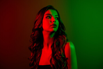 Portrait of attractive young lady model looking empty space isolated multicolor red green neon...