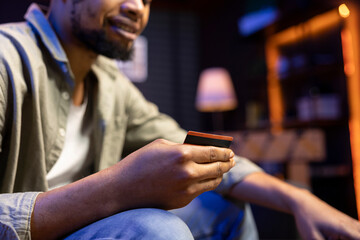 Casual young man at home entering card digits to renew an account subscription, managing the...