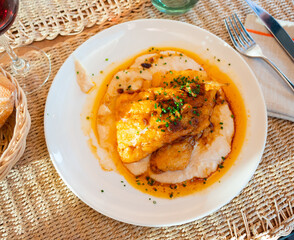 Few pieces of fried cod fillet and side dish of potatoes. Mashed potatoes with melted butter are...