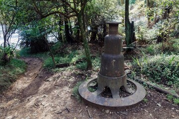 An old piece of machinery sits on a forest path in The Crown Mines, Karangahake, Coromandel...
