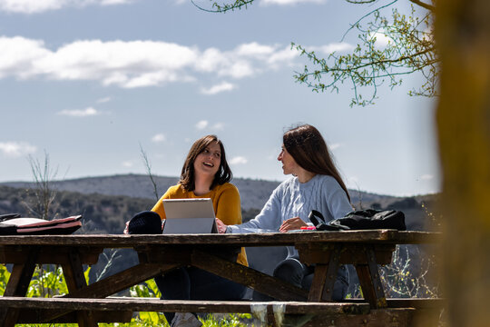 University students studying outdoors with tablet and discussing assignments