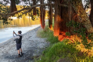 A photographer takes a photo in Whangamata, Coromandel Peninsula, New Zealand. He is capturing the...