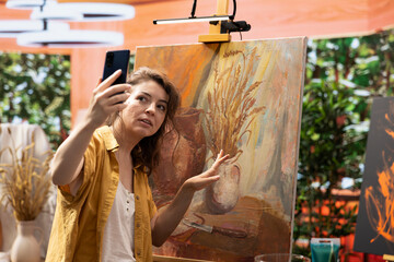 Confident painter presenting her new masterpiece on online vlog, creating content for reach and...
