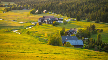 Evening light casts a warm glow over Jizerka Village in the Jizera Mountains. The tranquil...