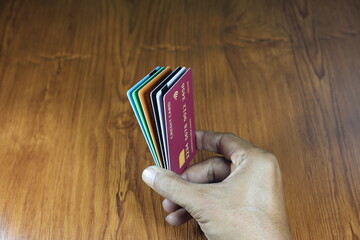 The right hand holds several dummy credit cards on a wooden patterned table.