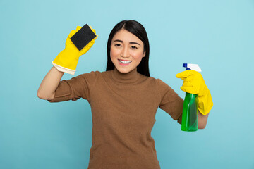 Asian housekeeper holding sponge and detergent spray bottle, ready to provide professional...