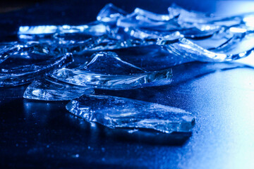 Broken Glass Shards on Dark Surface with Cold Blue Lighting
