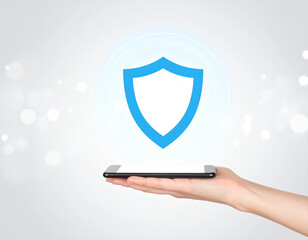 Modern shield icon represents security above smartphone held in hand against an abstract light background