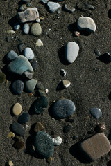 glossy stones washed by the sea wave shine from the rays of the sun on a summer day. pebbles on the city beach.the concept of environmental protection from pollution by petroleum products and plastics