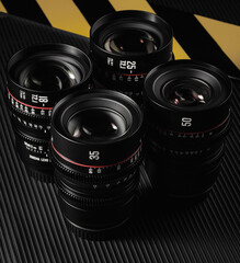 A set of four camera lenses with various focal lengths is arranged neatly. Each lens features...