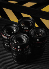 A set of four camera lenses with various focal lengths is arranged neatly. Each lens features...